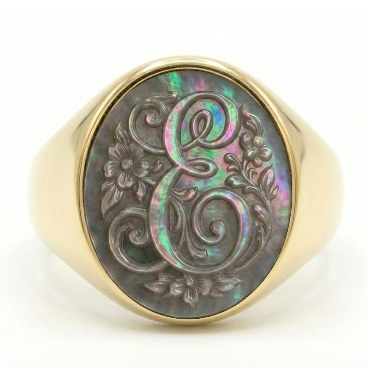 Anello con sigillo con monogramma della lettera E in corsivo e decorazioni floreali incise su madreperla grigia iridescente - signet ring featuring a cursive letter E monogram and floral motifs engraved on iridescent grey mother-of-pearl.