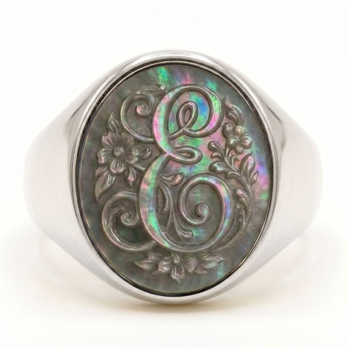 Anello con sigillo in argento con monogramma della lettera E in corsivo e decorazioni floreali incise su madreperla grigia iridescente - Silver signet ring featuring a cursive letter E monogram and floral motifs engraved on iridescent grey mother-of-pearl.